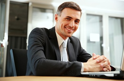 Happy businessman sitting with laptop at office